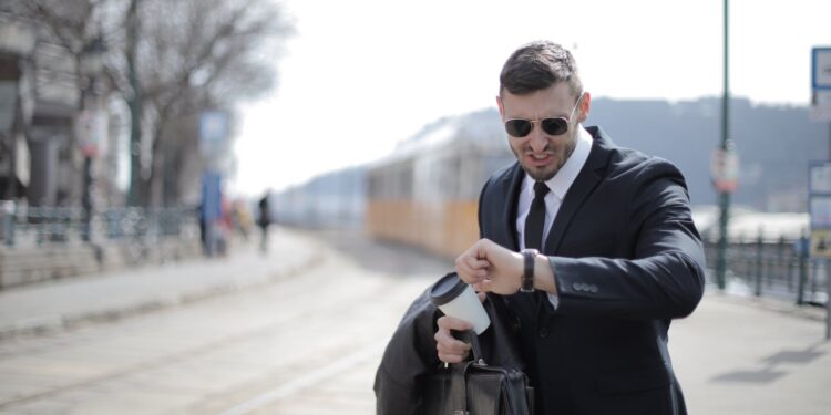 man in black suit jacket holding black leather bag