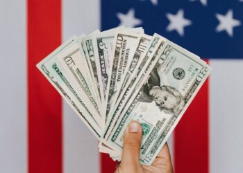 crop person demonstrating dollars against american flag