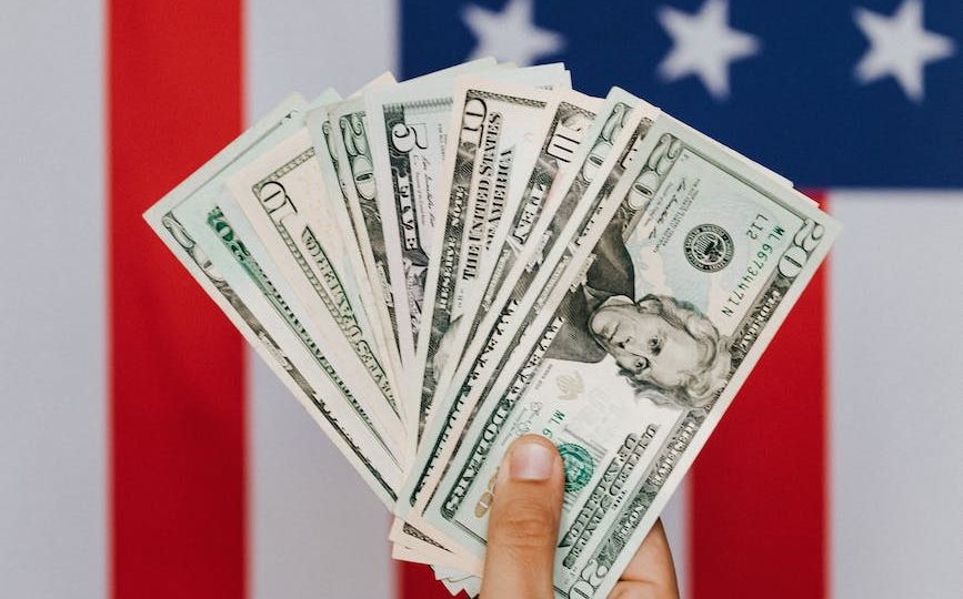 crop person demonstrating dollars against american flag