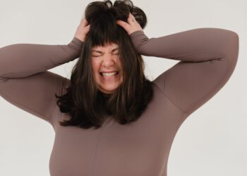 young obese woman rumpling hair with closed eyes in white studio