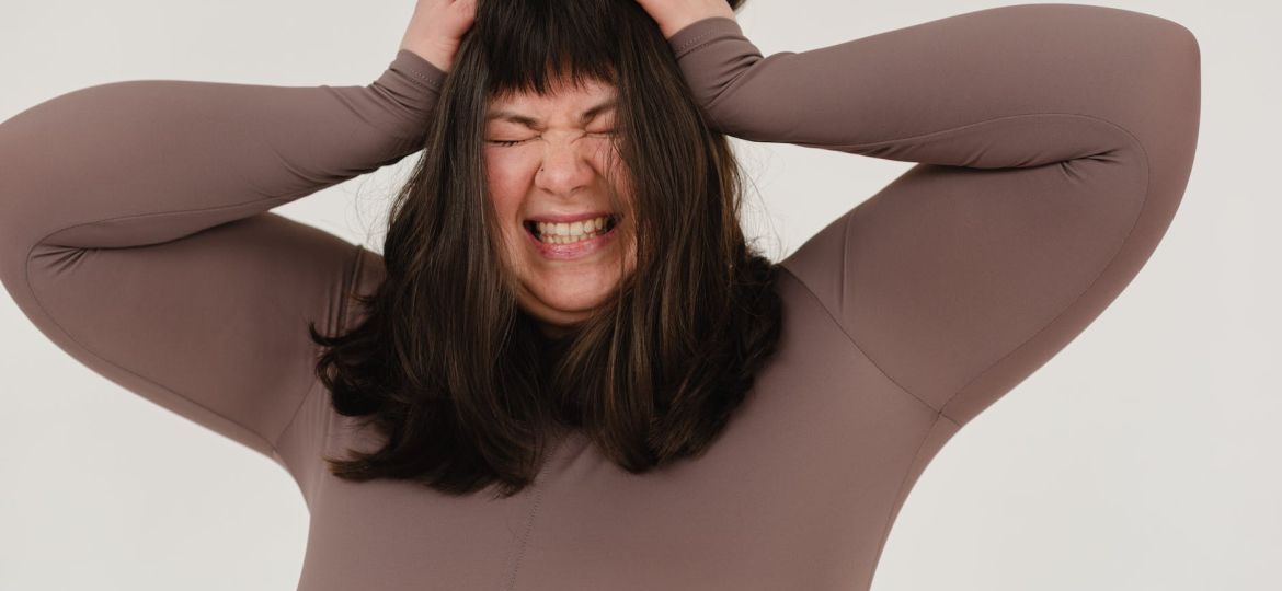 young obese woman rumpling hair with closed eyes in white studio